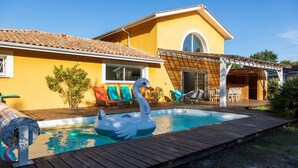 Piscina con flotador de cisne, terraza de madera y zona de estar al aire libre.