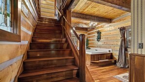 A wooden staircase leading to a bathroom with a bathtub and a shower area. - Cinnamon Valley - The Elk Lodge (Eureka Springs)