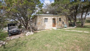 A stone house with a satellite dish, a jeep, and a small lawn.