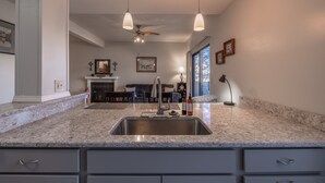 Cocina con encimera de granito, pileta de acero inoxidable e iluminación moderna.