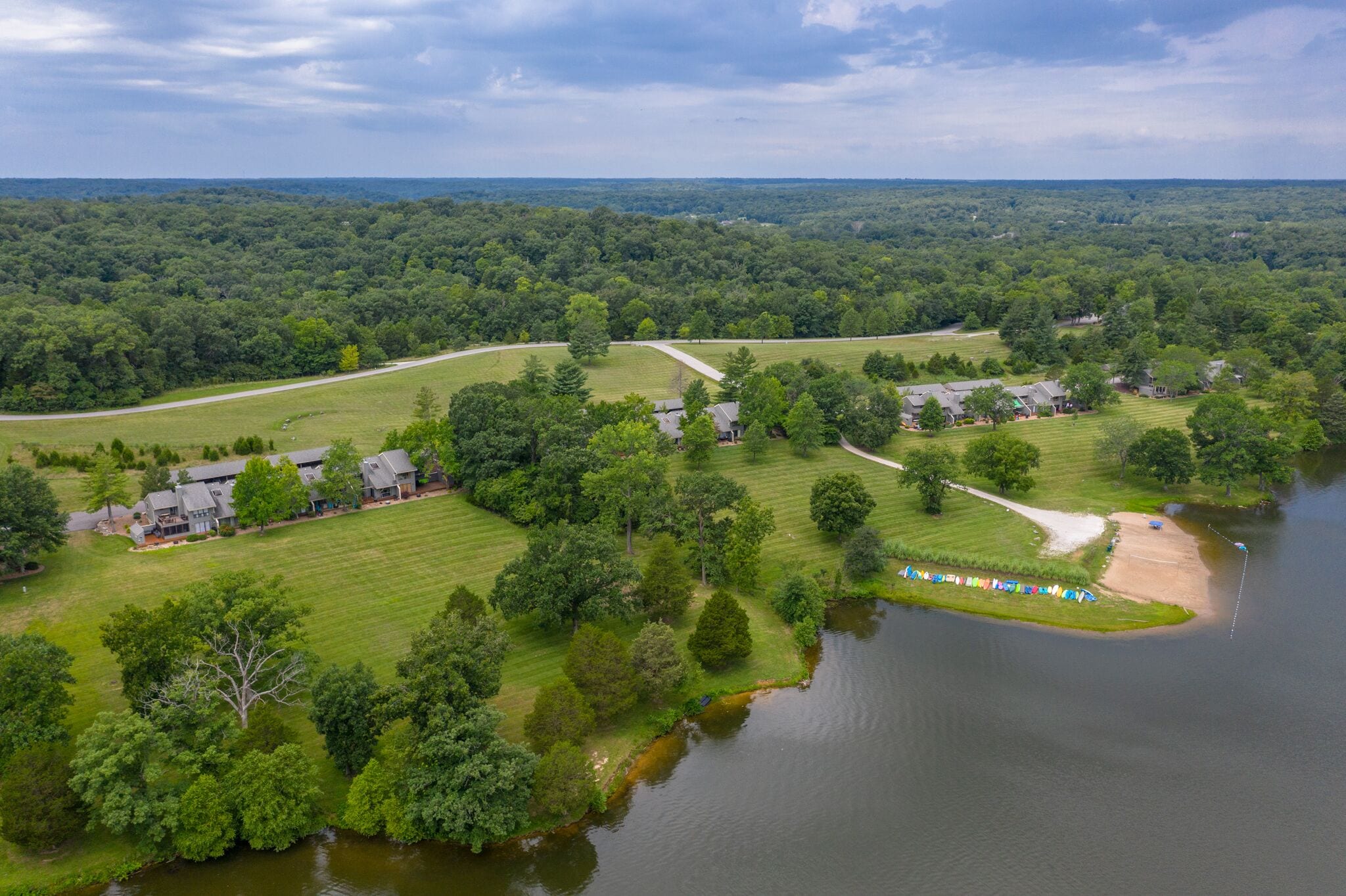 Vista aérea de una zona residencial con casas, un lago y un paisaje boscoso.