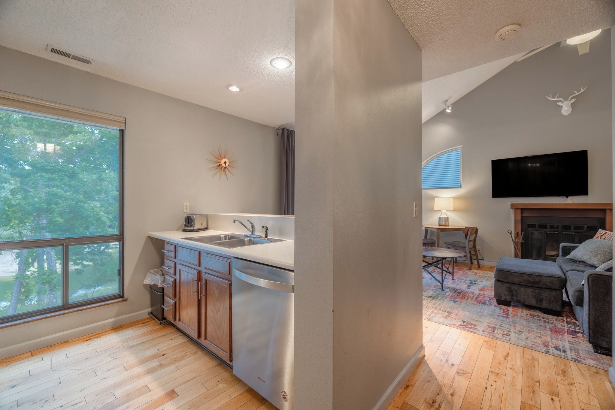 A modern kitchen with a large window, a built-in oven, and a sink.