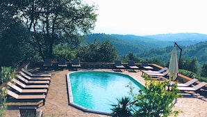 A pool area with lounge chairs and a view of the surrounding landscape.