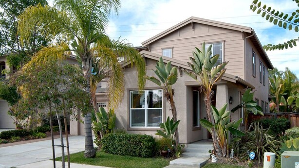 A two-story house with a front porch, a small garden with palm trees, and a clear sky. - Carlsbad treasure in Calavera Hills (carlsbad)