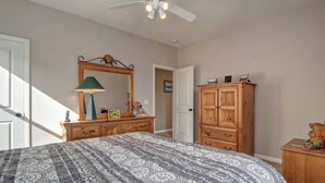 A bedroom with a bed, a dresser, a mirror, a ceiling fan, and a door. - Carlsbad treasure in Calavera Hills (carlsbad)