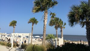 A beachside area with palm trees, beach umbrellas, and lounge chairs. - PRISTINE BEACH, GOLF, TENNIS!  BEAUTIFUL AND SPACIOUS 2BR COURTSIDE VILLA!  (Seabrook Island)