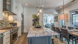 A modern kitchen with a central island, stainless steel appliances, and a dining area with a large window.