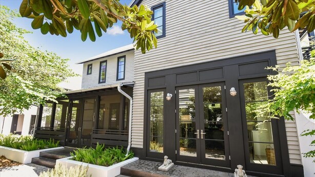 A modern two-story house with a dark front door, large windows, and a covered porch area.