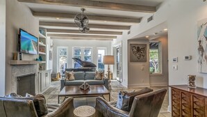 A spacious living room with a fireplace, a grand piano, and a large television.
