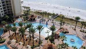 A resort with a pool area, palm trees, and a beach view.