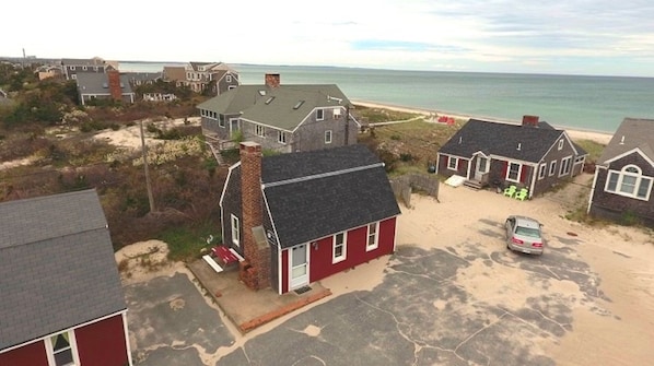 Un área residencial costera con casas, una playa de arena y vistas al océano.