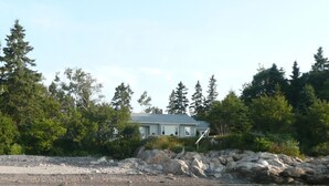 A house by a rocky shoreline with a view of the water and surrounding trees. - Ocean front house with two private beaches-- on a peninsula--spectacular views! (Milbridge)