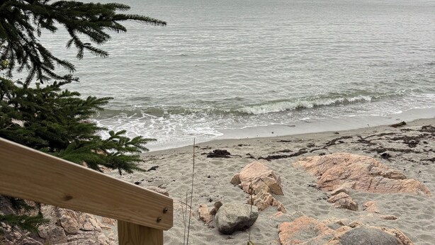 A wooden staircase leading to a rocky beach with a view of the sea and distant land. - Ocean front house with two private beaches-- on a peninsula--spectacular views! (Milbridge)