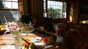 A dining table with a vase of flowers, a plate with pears, and a tray with jars. - Ocean front house with two private beaches-- on a peninsula--spectacular views! (Milbridge)