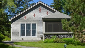 A single-story house with a gabled roof, a front porch with decorative metal railing, and a small front yard with a pathway leading to the entrance. - Quiet, peaceful, great central location.  Come visit! (Mt. Desert)