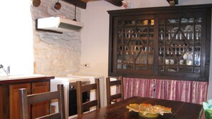 A kitchen with a wooden table, chairs, a built-in oven, and a cabinet with glass doors. - Authentic 19th century house near Vans (Malons-Et-Elze)