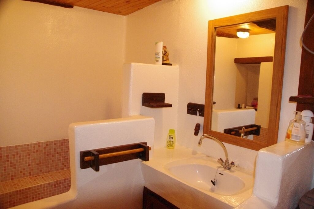 Une salle de bain avec un lavabo blanc, un miroir, un porte-serviettes et une petite étagère contenant des articles de toilette.