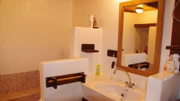 Une salle de bain avec un lavabo blanc, un miroir, un porte-serviettes et une petite étagère contenant des articles de toilette.