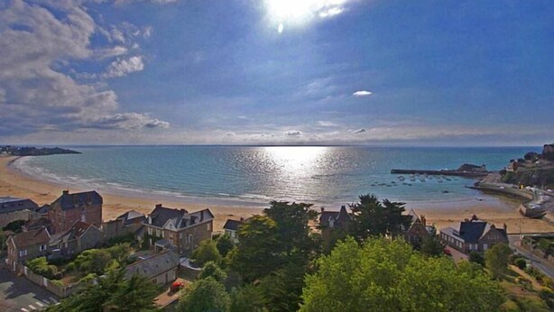 A coastal town with a beach, houses, and a clear sky.