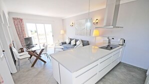 Una cucina moderna con un'isola grande, mobili bianchi e un'area pranzo con tavolo e sedie.