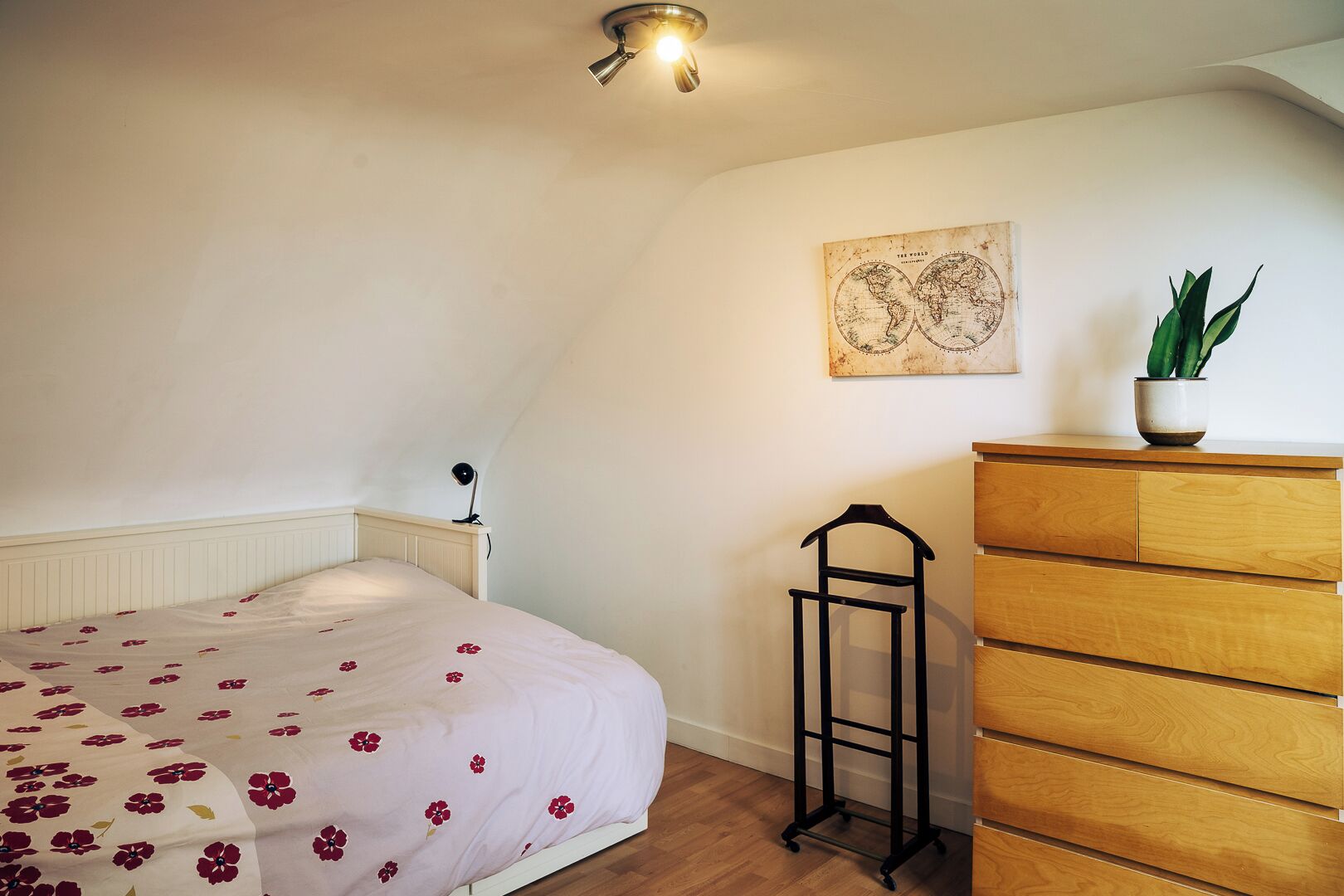 Une chambre à coucher avec un lit, une commode et une carte accrochée au mur.