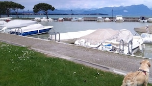 A marina with boats docked, a grassy area in the foreground, and mountains in the background. - Pretty Casa Margherita, Lugana di Sirmione for your relaxation (Sirmione)