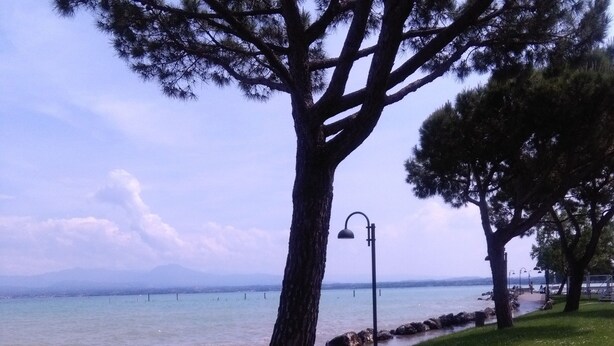 A park with a bench, a lamp post, and a view of the water. - Pretty Casa Margherita, Lugana di Sirmione for your relaxation (Sirmione)