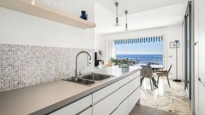 A modern kitchen with a large island, double sink, and a view of the ocean.