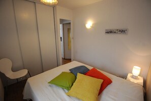 Une chambre à coucher comprenant un lit, une chaise, une table de chevet avec une lampe et un luminaire fixé au mur.