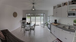 Una cocina moderna con armarios blancos, microondas integrado y un ventanal grande.