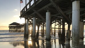 Un muelle con estructura de madera y pilares de hormigón que se adentran en el agua.