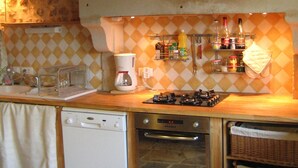 A compact kitchen with a dishwasher, oven, and a small countertop with a coffee maker and a gas stove. - Nature, Peace and Authenticity... (Montalembert)