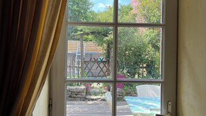 A white door with a window, leading to an outdoor area with a wooden deck, a white chair, and a table. - Nature, Peace and Authenticity... (Montalembert)