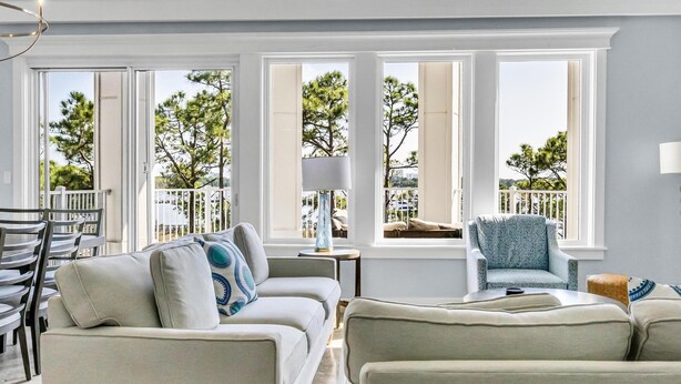 A spacious living room with a high ceiling, large windows, and a balcony. - Luxurious Bayfront Penthouse w/ Stunning Views (Miramar Beach)