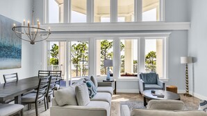 A spacious living area with a dining table, sofas, and a chandelier. - Luxurious Bayfront Penthouse w/ Stunning Views (Miramar Beach)