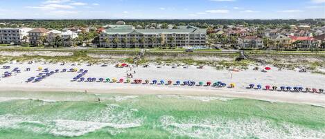 A beach resort with a large building, a sandy beach, and clear turquoise water.