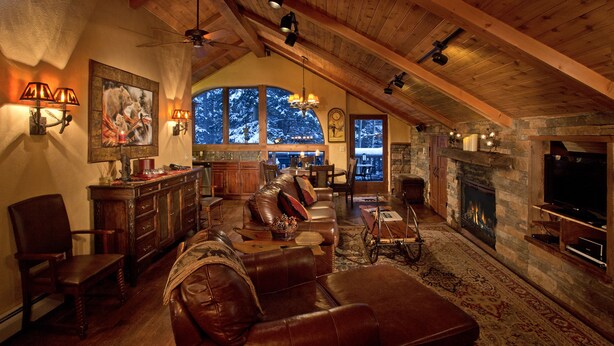 Un ampio loft con soffitto alto, camino, arredi in pelle e una grande finestra con vista su un paesaggio innevato.
