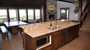 Una cocina amplia con encimeras de granito, horno empotrado y chimenea de piedra.