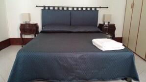 A neatly made bed with a blue bedspread and pillows, two bedside tables with lamps, and a wooden headboard.