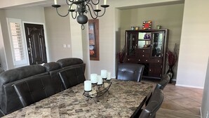 Un espace repas avec une table en marbre, des fauteuils en cuir et un lustre.