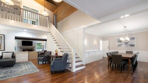 A spacious living area with a wooden staircase, a dining table with chairs, and a kitchen area with white cabinets. - "New" Lake Michigan R & R Recently Completed Major Rehab (Union Pier)