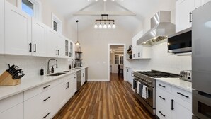 A modern kitchen with white cabinetry, a wooden floor, and stainless steel appliances. - "New" Lake Michigan R & R Recently Completed Major Rehab (Union Pier)