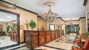 Un vestíbulo de hotel con una recepción, una araña y un mostrador de registro.