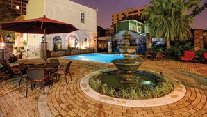 Un patio con piscina, una fuente y mobiliario de exterior.