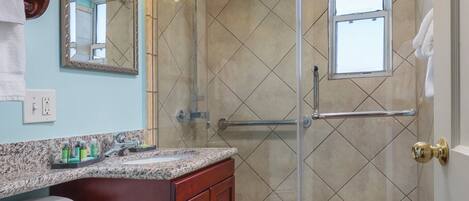 A bathroom with a toilet, sink, vanity, and a glass-enclosed shower area.