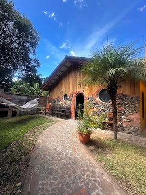 Un bâtiment rustique avec une façade en pierre, une porte en bois et un chemin pavé menant à l’entrée.