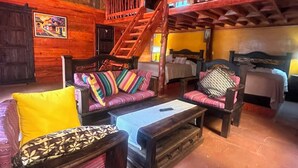 Ein rustikaler Raum mit Holzwänden, einer Treppe, einer Sofagarnitur und einem Bett.
