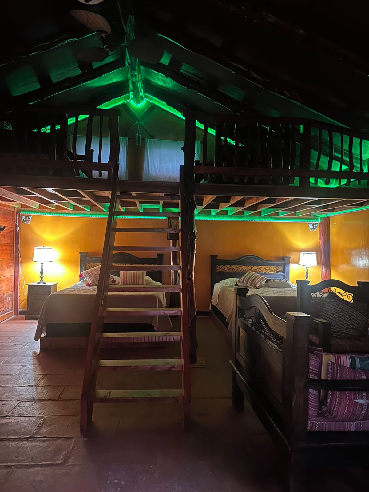 Een kamer met stapelbedden, een ladder en twee bedlampjes.