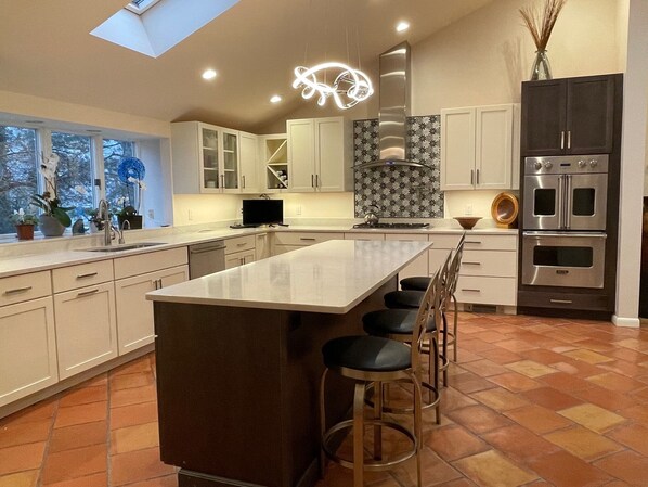 Una cocina moderna con una isla central, electrodomésticos de acero inoxidable y un tragaluz.