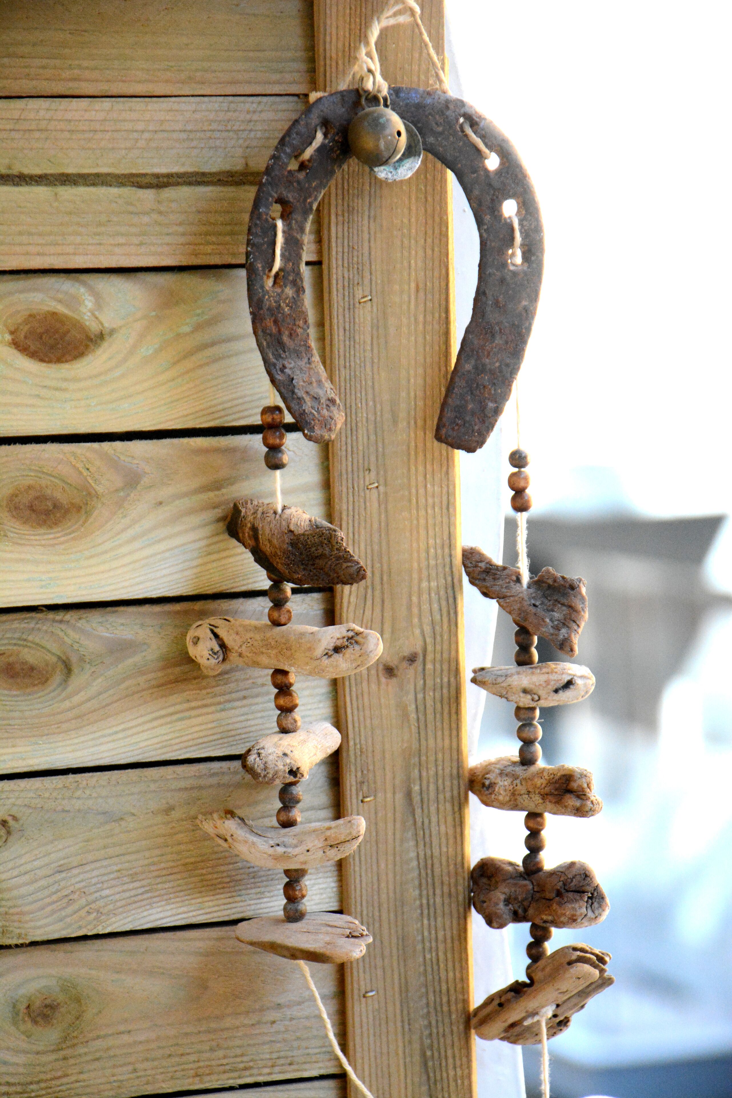 A rustic wooden wall with a decorative metal horseshoe and wooden beads.
